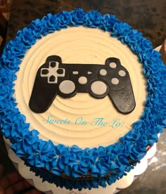 a cake decorated with blue and white frosting has a controller on the top that says, games on the go