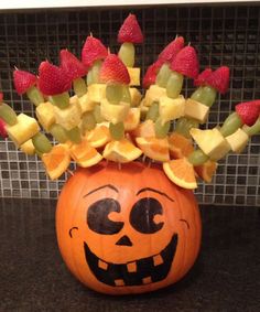 a carved pumpkin with fruit on it's head and strawberries in the top