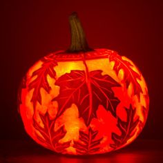 a carved pumpkin sitting on top of a table next to a red background with leaves