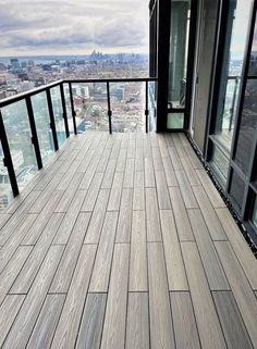 a balcony with wooden flooring and black railings overlooking the cityscape in the distance