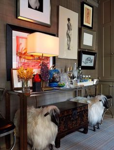 two sheep are standing in front of a table with pictures on the wall behind it