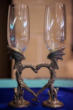 two wine glasses sitting next to each other on top of a blue cloth covered table