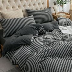 an unmade bed with black and white striped comforter, pillows and blankets on it