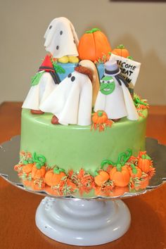 a halloween cake with ghost and pumpkins on the top is sitting on a table