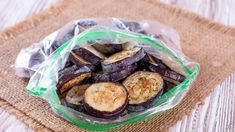 a bag filled with sliced eggplant sitting on top of a wooden table next to a fork