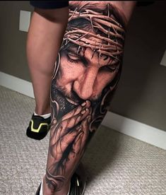 a person with tattoos on their legs and feet is wearing a crown of jesus's head