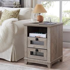 a white couch sitting in a living room next to a table with two drawers on it