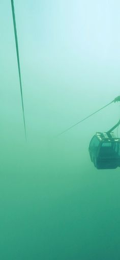 a boat floating in the ocean on a foggy day with power lines above it