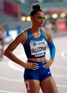 a woman standing on top of a track in a blue suit with her hands on her hips