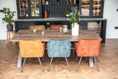 a dining room table with four chairs and a bar in the back ground behind it