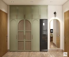 an empty room with wooden floors and green cupboards on the wall, next to a mirror