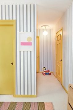 an empty room with striped walls and rugs on the floor next to a yellow door