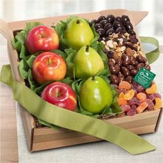 an assortment of fruits and nuts in a box with green ribbon on the table top