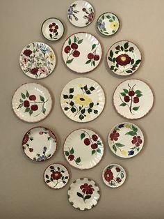 many plates are arranged in the shape of a flowered design on a wall above them