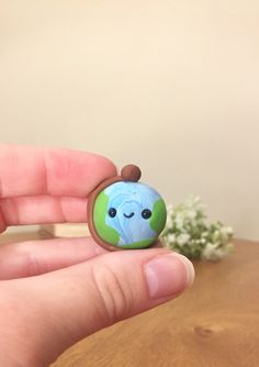 a hand holding a small blue and green broccoli bead