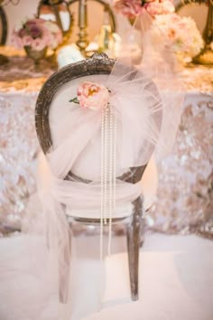 a chair with a veil and flowers on it sitting in front of a chandelier