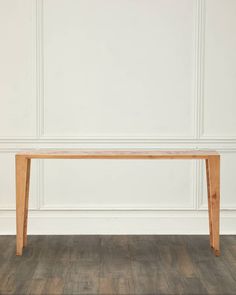 a wooden table sitting on top of a hard wood floor next to a white wall