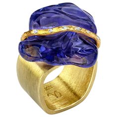 Rough, polished "Baroque” Tanzanite gemstone set with a Diamond and 22k yellow gold ribbon on an 18k gold square-shaped cocktail ring. Size 7. Unique and one-of-a-kind artisan statement ring featuring a magnificent bluish-purple Tanzanite. Statement Rings Diamond, Gold Baroque, Vintage Cocktail Ring, Fancy Jewellery Designs, Bleu Violet, Tanzanite Diamond, Gold Statement Ring, Jewels Rings, Gold Cocktail Ring