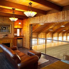 an empty living room with wood paneling and leather furniture in the middle of it