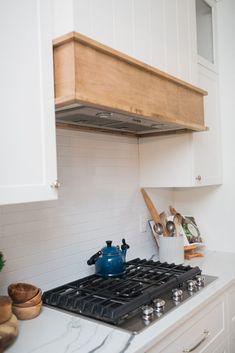 a stove top oven sitting inside of a kitchen next to white cabinets and counter tops