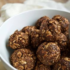 a white bowl filled with chocolate and oatmeal balls on top of a table