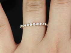 a woman's hand with a diamond ring on top of her finger and the other half of her wedding band