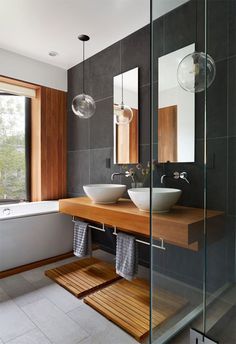 two white bowls are sitting on a wooden counter in front of a bathtub and window