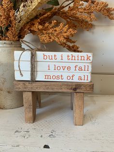 a wooden bench sitting next to a potted plant and vase filled with dried flowers