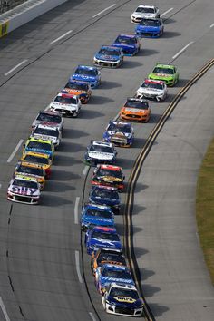 a group of cars that are driving down a track together in a line on the side of the road