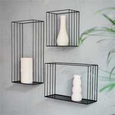 three black metal shelves with vases on them