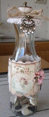 a glass vase filled with lots of shells and lace on top of a tablecloth