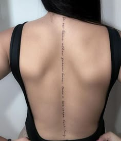 the back of a woman's neck with writing on it and her hands behind her