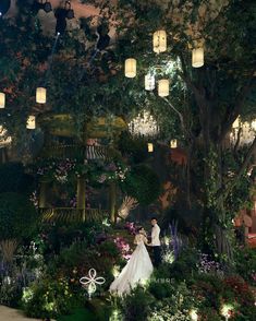 a bride and groom standing in front of a garden with lanterns hanging from the ceiling