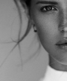 a black and white photo of a woman with freckles on her face looking at the camera