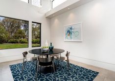 a dining room table and chairs in front of two large windows that look out onto the yard