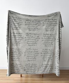 a blanket with writing on it sitting on top of a wooden floor next to a wall