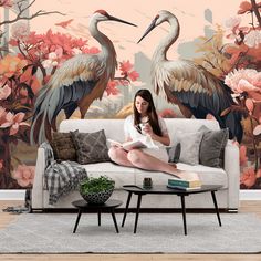 a woman sitting on a couch in front of a wall mural with two large birds