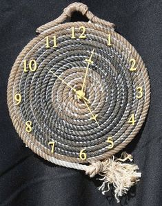 a clock made out of rope with numbers on the front and sides, sitting on a black background