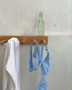 two towels hanging on a wooden rack next to a bottle and towel holder with hooks