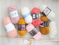 several skeins of yarn are arranged on a white surface next to a knitting needle