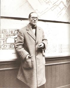 an old photo of a man standing in front of a wall