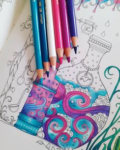 some colored pencils sitting on top of a coloring book with an image of a vase