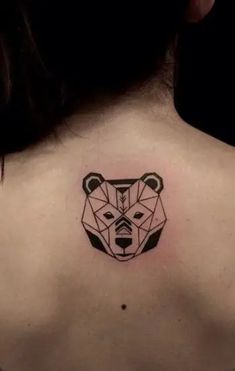 the back of a woman's neck with a geometric bear head tattoo on it