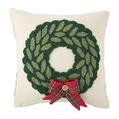 a christmas wreath pillow with a red bow on the front and green wreath on the back