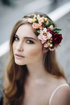 a woman with flowers in her hair wearing a flower headband on her head and looking off to the side