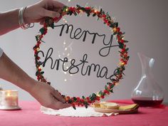 a person holding up a merry christmas sign on a table with other items around it