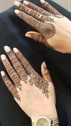 two hands with henna tattoos on them and a watch in the middle one hand