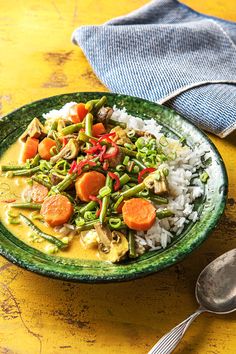 a green plate topped with rice and veggies on top of a yellow table