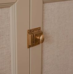 a close up of a door handle on a white cabinet with beige linen behind it