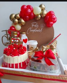 two cakes in a box with red and white decorations on top, along with other items